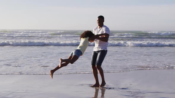 African american father and his daughter playing on the beach