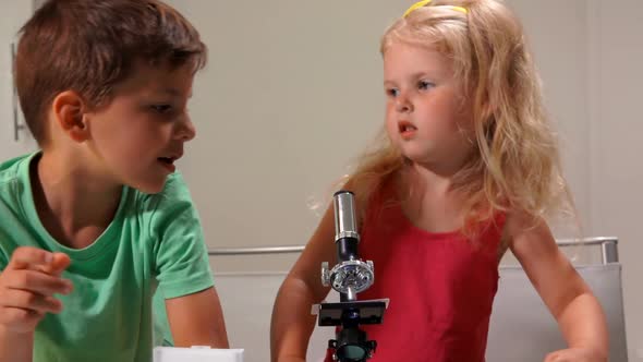 Cute Little Girl and Boy in Green Tshirt are Sharing a Microscope