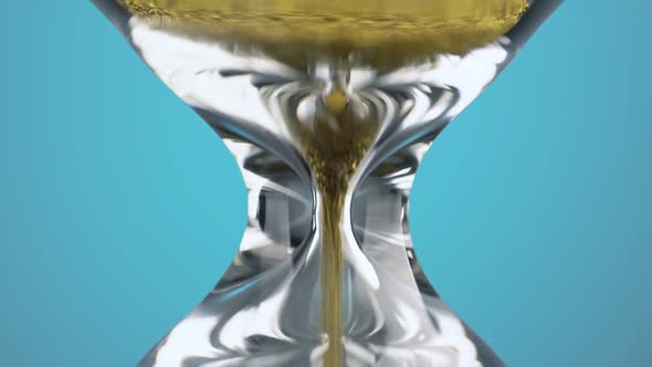 An Hourglass Made of Yellow Metal Shavings Passes Through a Funnel Symbolizing the Concept of Time