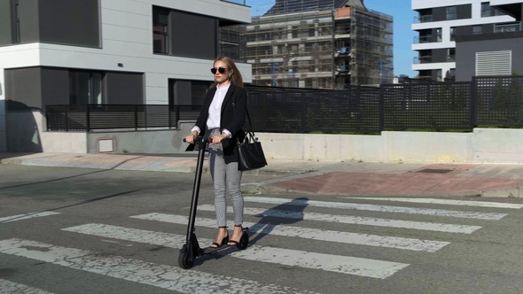 Woman crossing the street on electric scooter