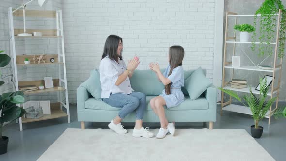 Happy Woman and Her Daughter Playing Together Patty Resting on Sofa at Home