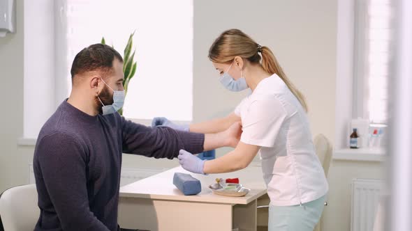 In a Modern Clinic Doctor Preparing the Patient To Take Blood Taste