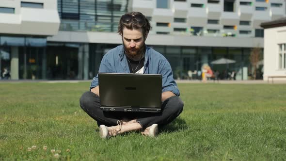 Man Uses Laptop on Grass