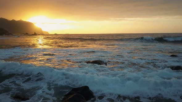 Aerial View. Ocean Waves Crash on Rocks and Spray in Beautiful Sunset Light Near Benijo Beach