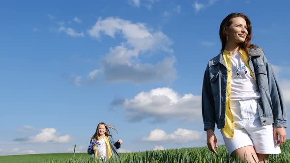 Mom and Daughter Walk in a Green Field of Young Wheat