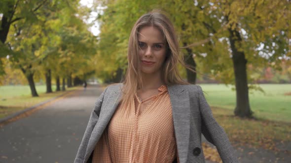 Close-up of a Slim Caucasian Woman in Checkered Jacket and Mustard Dress Turning Around and