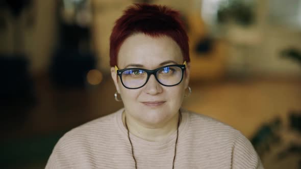 Portrait Middleaged Business Woman in Home Office in Glasses Slight Smile