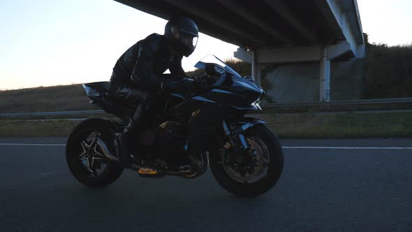 Man Riding on Modern Sport Motorbike at Highway with Sun Flare at Background. Motorcyclist Racing