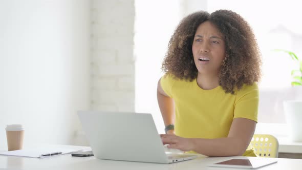 African Woman having Back Pain while using Laptop in Office