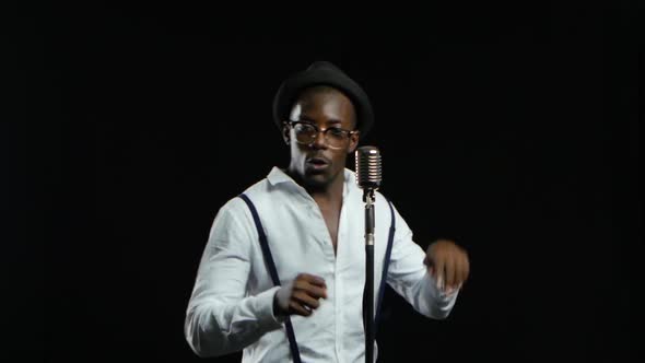 Man African American Singer Sings Into a Microphone and Dance. Black Background