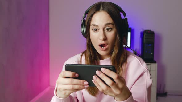 Lifestyle Young Woman in Headphones Play Game and is Perplexed
