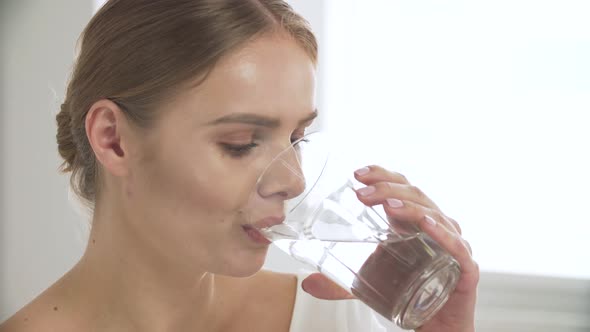 Woman Drinking Water From Glass And Looking At Camera