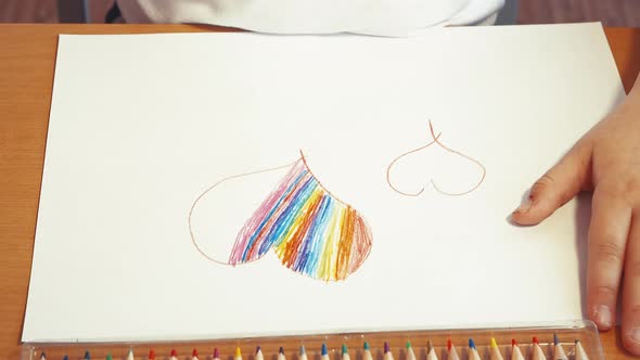 A Rainbow Heart is Drawn By Children's Hands in Closeup with a Colored Pencil
