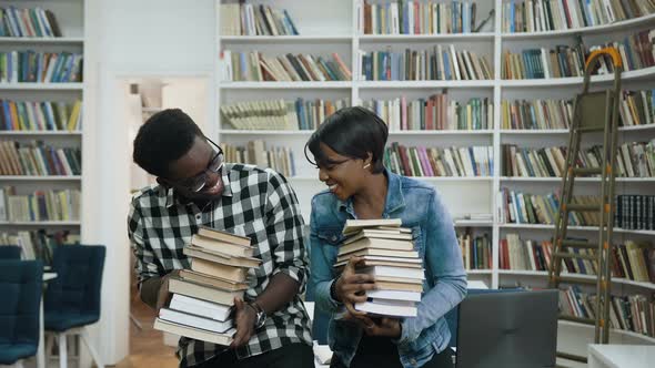 Young African Couple Holding a Bunch of Books in the Hands 