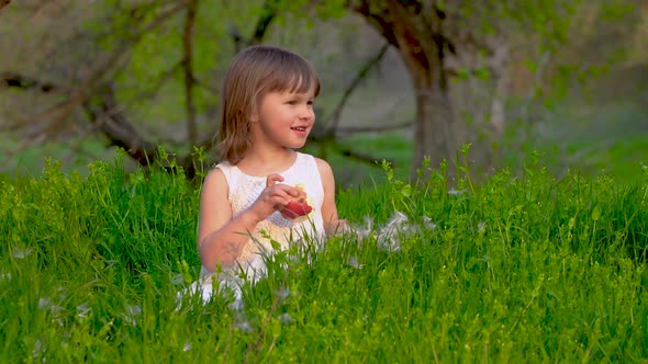 Girl Sitting on the Grass and Eating an Apple