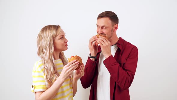 Guy with a Girl on a White Background Bite a Hamburger