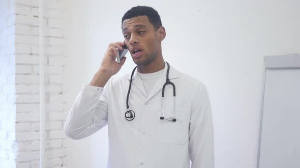 Standing African American Doctor Talking on Mobile Phone in Hospital