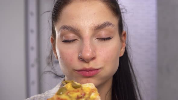 Young Woman Biting Pizza Slices and Looking at Camera