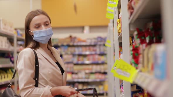 A young woman in a medical mask buys food in a supermarket during the Covid-19 coronavirus