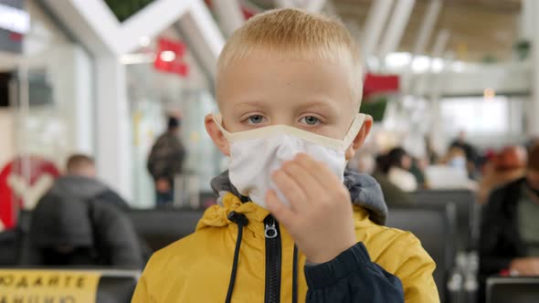 Closeup of a Small Boy in a Medical Mask in the Airport Waiting Room