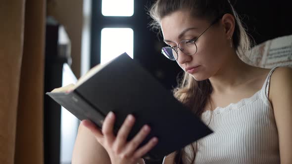 girl with glasses reads a book