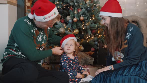 Lovely Couple Playing with Their Little Daughter Near Christmas Tree