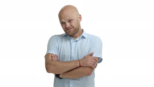 Young Reluctant Man with Bald Head and Beard Cross Arms Chest and Looking Around Indecisive Standing