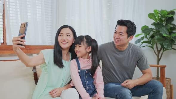 Asian happy family, father and mother with little kid daughter talking in video conference at home.