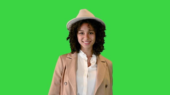 Young African American Woman in a Hat Stumbled While Walking and Smiling on a Green Screen, Chroma