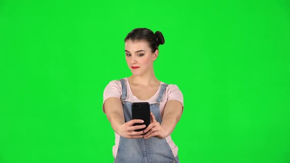 Young Woman Makes Selfie on Mobile Phone Then Looking Photos on Green Screen