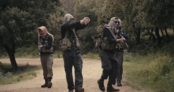 Squad of armed terrorists patrolling a forest area during combat