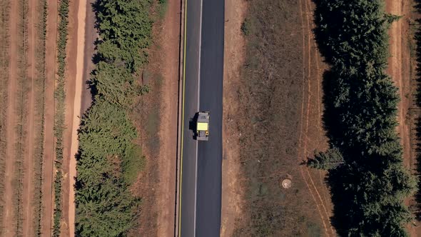 Road roller pressing fresh put Asphalt on a new road, Aerial follow footage.