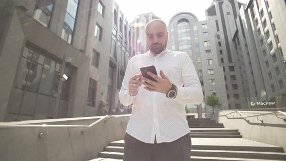 A Businessman Near a Business Center Communicates on the Phone