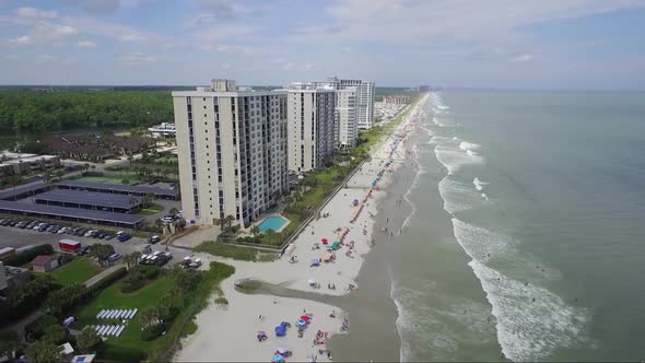 Flying towards tall ocean-front resorts near the beach in summer