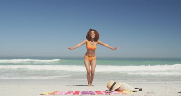 African american woman jumping at beach