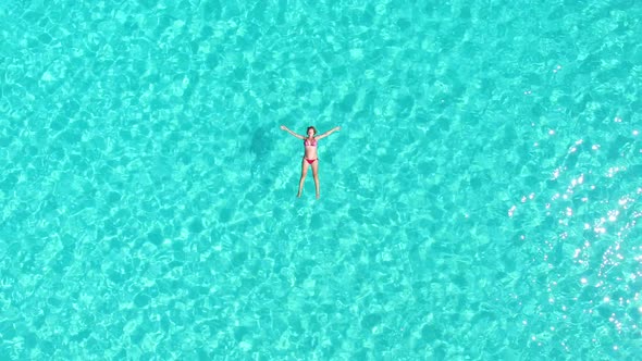 Aerial view of an attractive woman floating in crystal clear sea