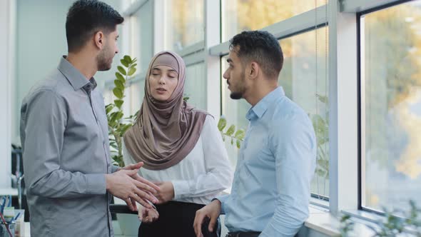 Multiethnic Colleagues Arab Muslim Woman in Hijab and Two Indian Millennial Male Discuss Corporate