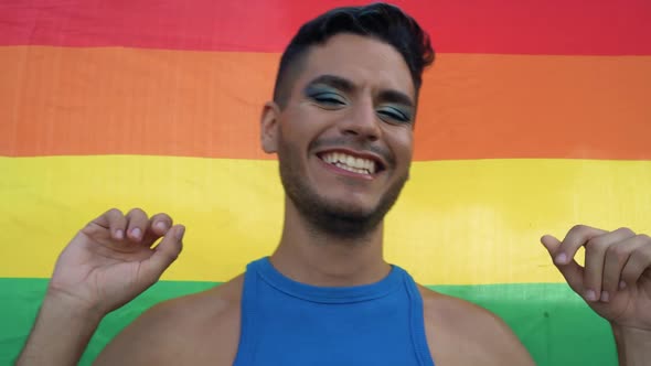 Happy homosexual man celebrating gay pride with rainbow flag symbol of LGBTQ community