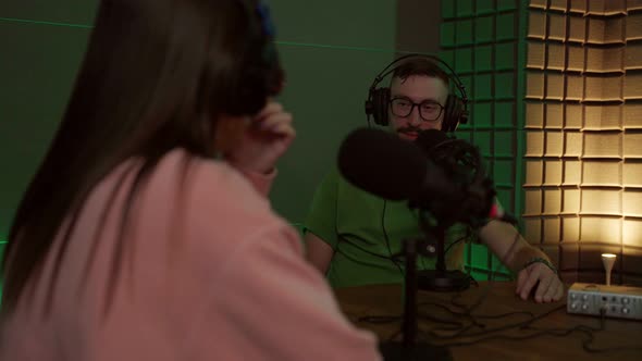 Young man talking in mic while recording podcast with crop coworker