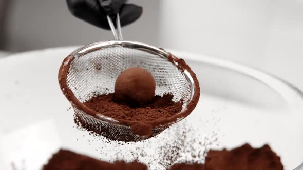 Closeup Chocolatier Making Traditional Dark Chocolate Truffle Dusted with Powder