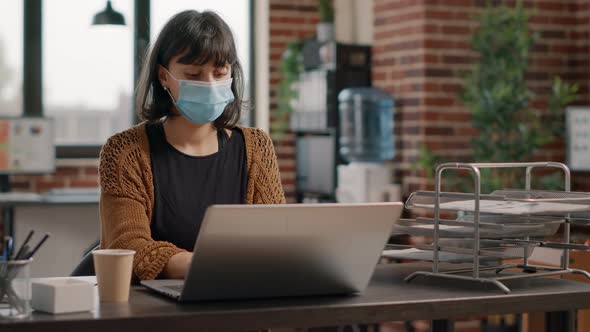Portrait of Employee with Face Mask Using Laptop to Work