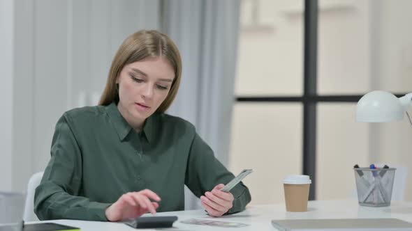 Woman Using Calculator While Counting Dollars