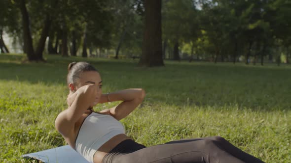 Active Sporty Fit Woman Doing Abs Crunches in Park