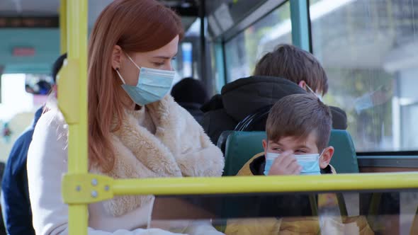 Woman in Place with Little Boy Ride Bus To Medical Mask on Face To Protect Against Virus and