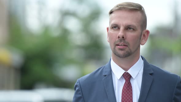 Happy Blonde Businessman Smiling While Thinking Outdoors