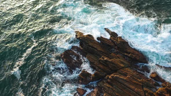 Ocean Waves Crash Against Stony Rocks During Sunrise on the Island of Sri Lanka. Aerial View