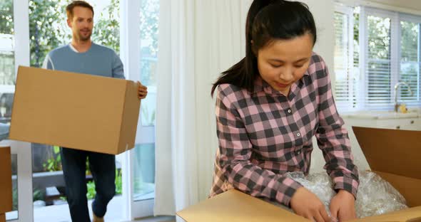Pregnant couple unpacking boxes in their new house 