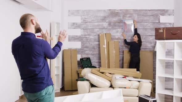 Caucasian Boyfriend Telling His Girlfriend How To Hang Picture in the Wall