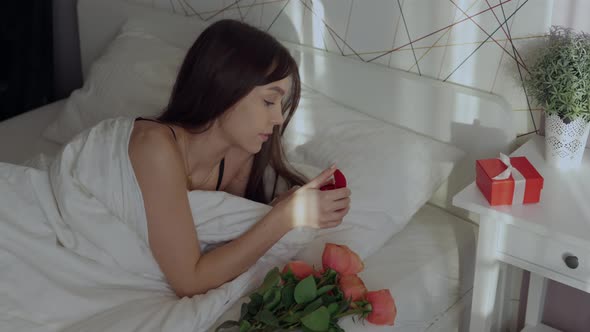 Pretty Caucasian Woman Opening Red Ring Box in Bed Surprising Emotions Camera