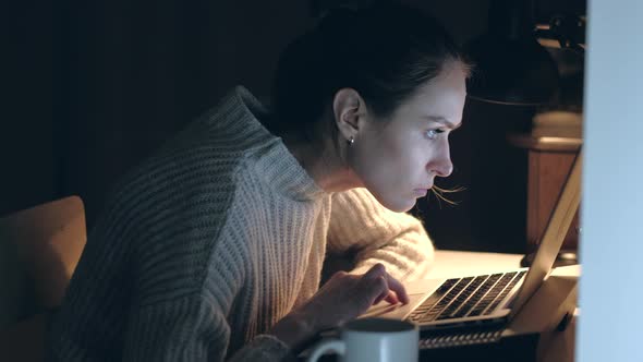 Active Woman freelancer working at night at the notebook.